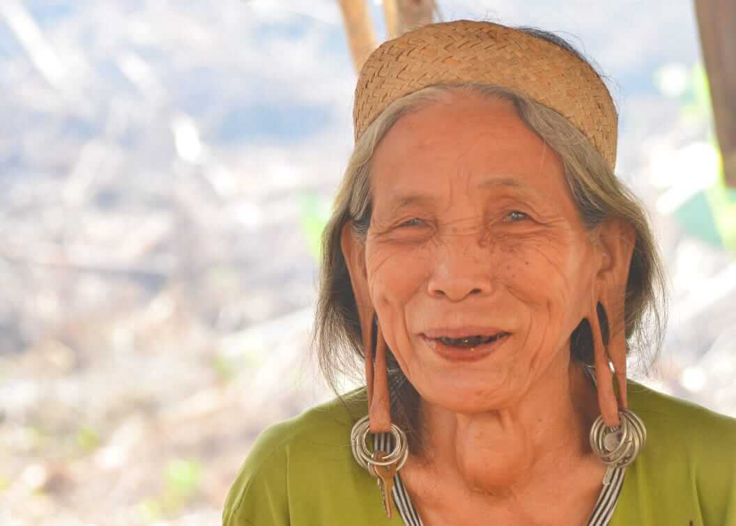 Potret dekat wajah wanita Dayak dengan anting panjang tradisional dan ekspresi anggun penuh makna.