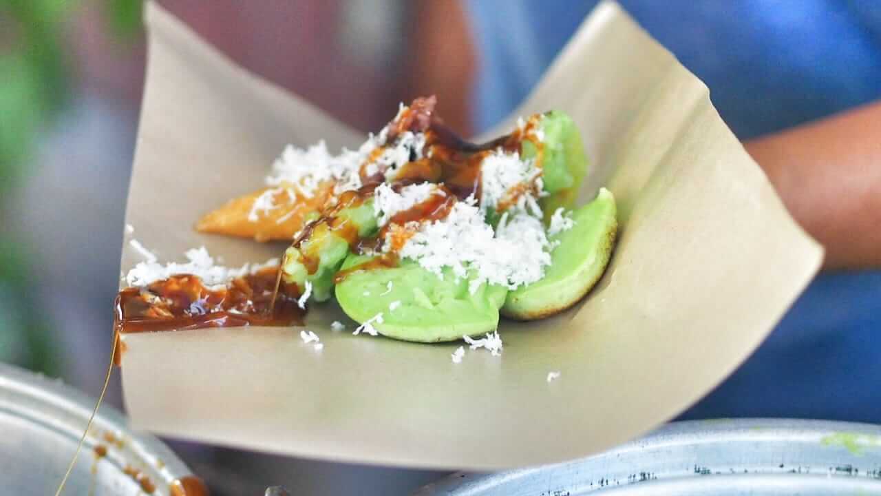 Jajan Bali tradisional terdiri dari ketan merah, pisang rai, dan laklak, disajikan dengan siraman gula merah yang harum.
