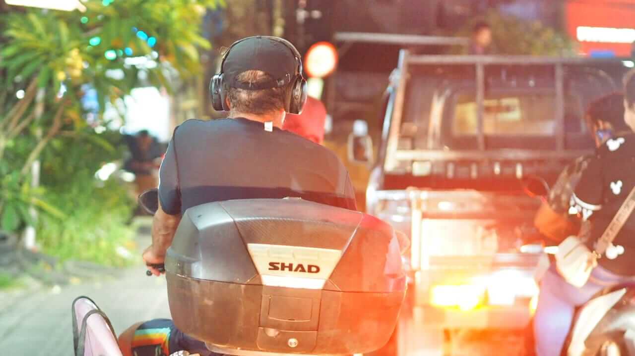 Turis asing mengendarai motor tanpa helm dan memakai earphone di persimpangan lampu merah Ungasan, Bali.