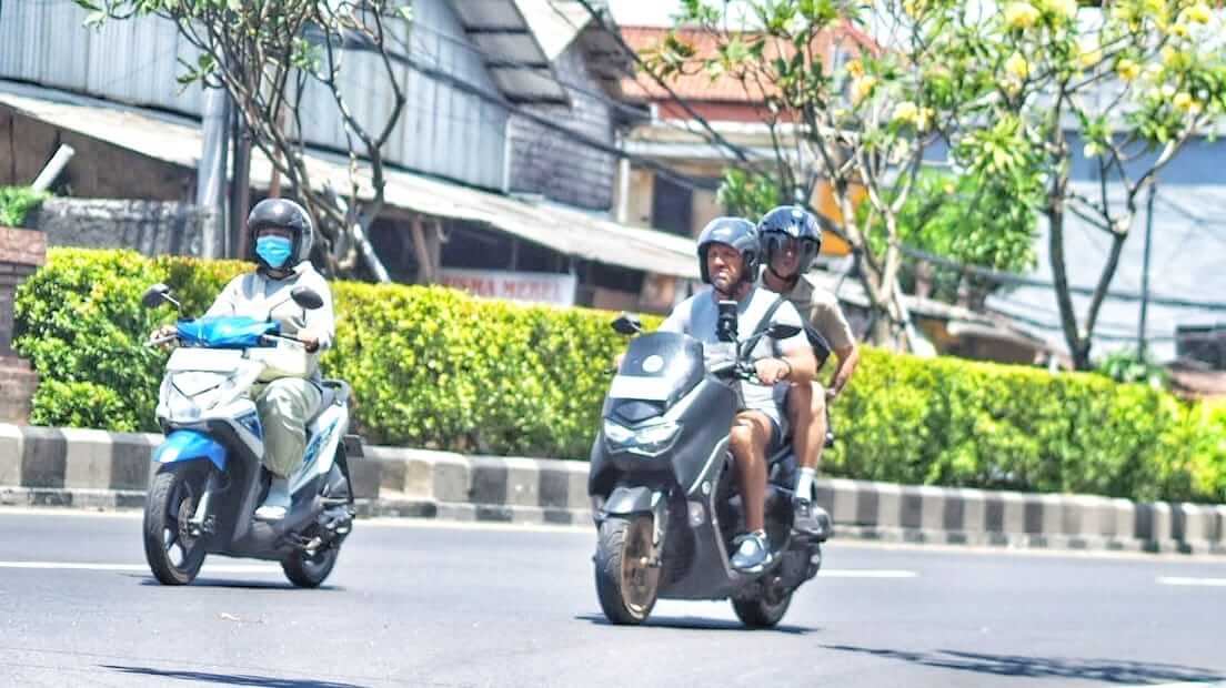 Wisatawan asing mengendarai motor sewaan saat menjelajahi Bali, solusi praktis menuju destinasi wisata tersembunyi.