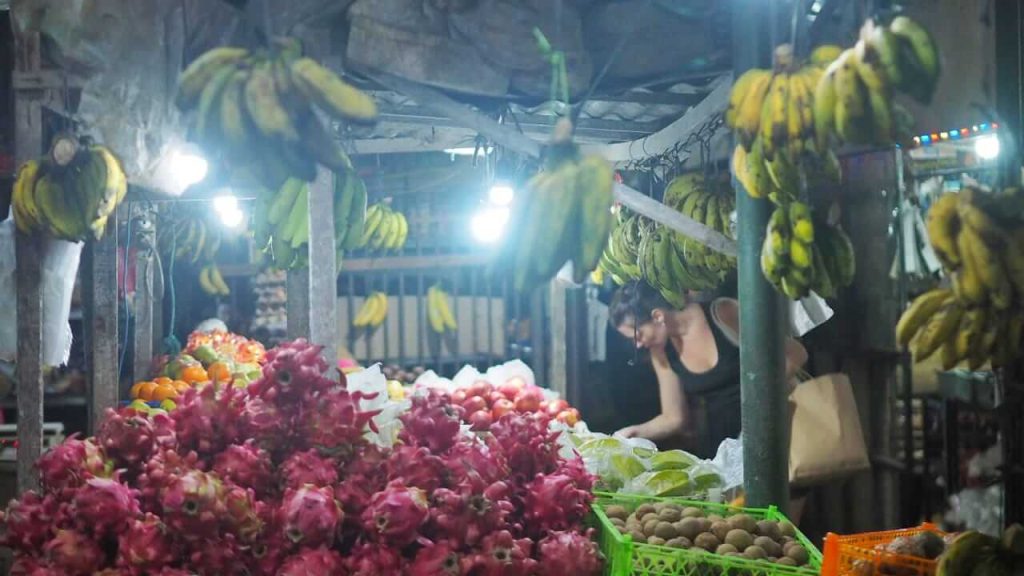 Wisatawan membeli buah lokal langsung dari pedagang pasar tradisional.