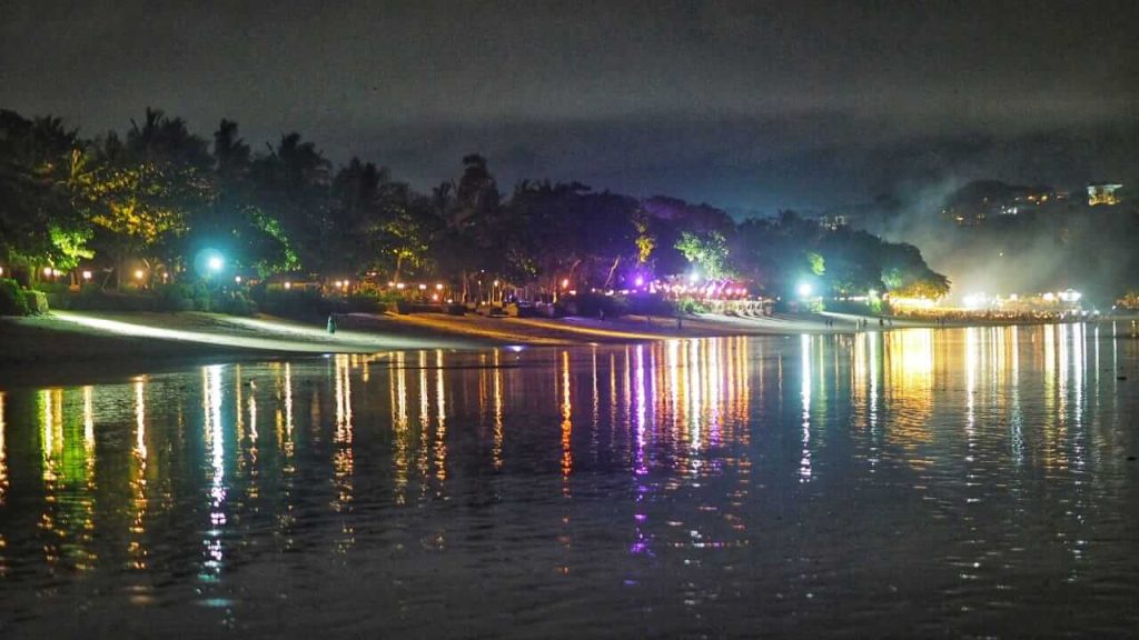 Pantulan cahaya lampu di permukaan pantai Jimbaran saat malam hari.