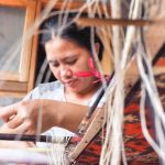 Proses pengikatan benang pada kain tenun ikat yang memerlukan presisi tinggi untuk menjaga keutuhan motif.