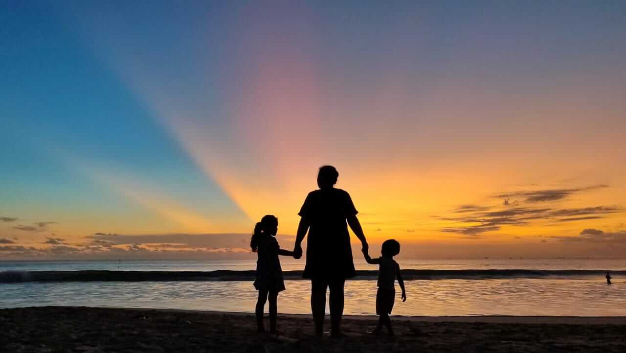 Langit senja berwarna keemasan saat matahari tenggelam di cakrawala Pantai Jimbaran, Bali.