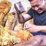 Komang Mane, pengrajin ukir kayu Bali, tersenyum saat mengerjakan karya seni ukirannya.