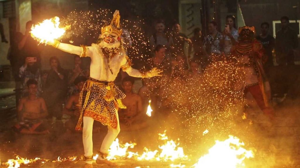Penari memerankan tokoh Hanoman sedang berinteraksi dengan api dalam pertunjukan tari Kecak Bali.