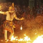 Penari memerankan tokoh Hanoman sedang berinteraksi dengan api dalam pertunjukan tari Kecak Bali.