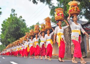 Wanita Bali berjalan anggun membawa gebogan berisi buah dan jajanan tradisional dalam prosesi adat.