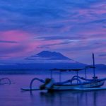 Pagi hari di Pantai Mertasari dengan gradasi langit indah dan siluet Gunung Agung di kejauhan.