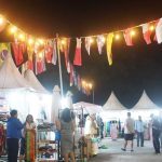 Wisatawan asing tertarik melihat-lihat produk baju UMKM lokal di stand Pasar Rakyat Bali Collection.