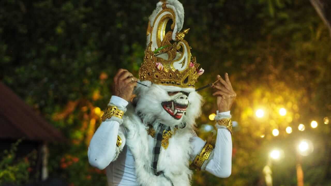 Pemeran tokoh Hanoman memasang topeng di balik layar sebelum pertunjukan dimulai.