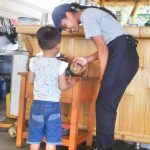 Karyawati melayani anak pelanggan yang penasaran melihat deretan cookies di area kasir.