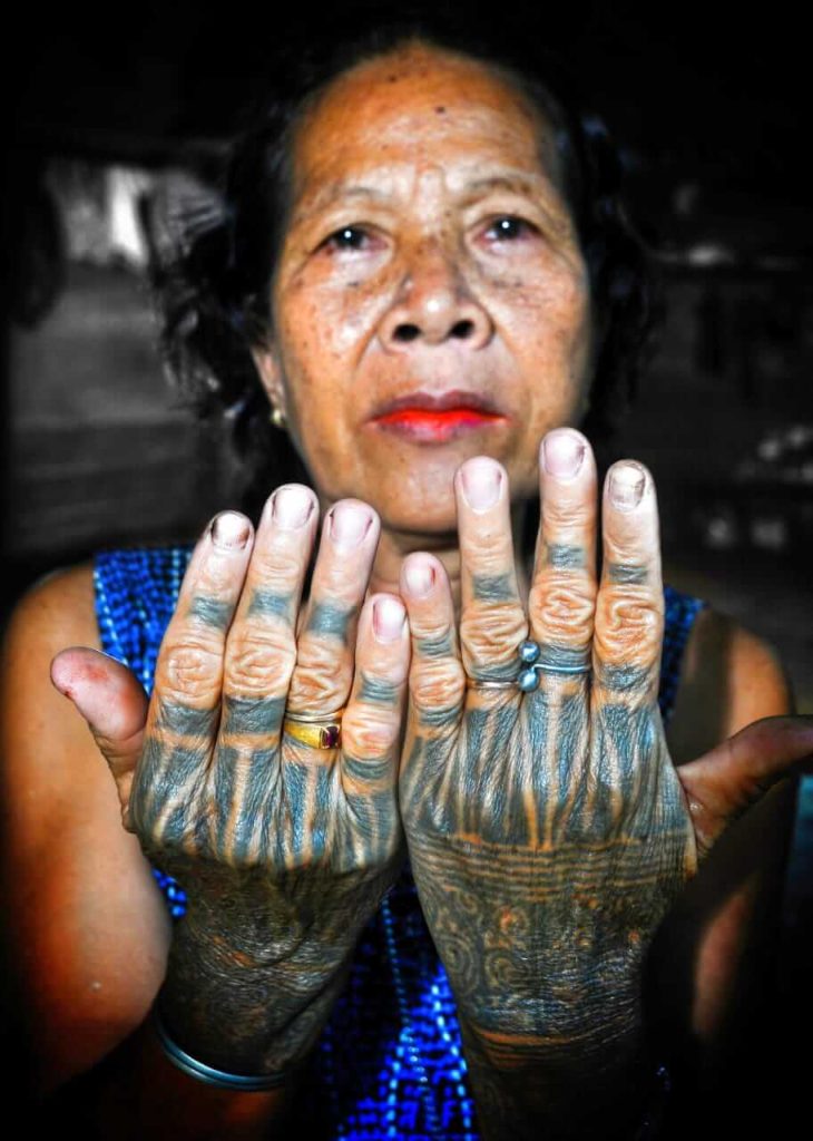 Seorang nenek menunjukkan motif tato tradisional yang menghiasi tangan kirinya.