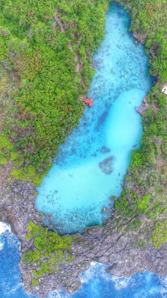 Pemandangan Danau Weekuri di Sumba Barat Daya dengan air biru jernih, dikelilingi savana dan tebing karang.