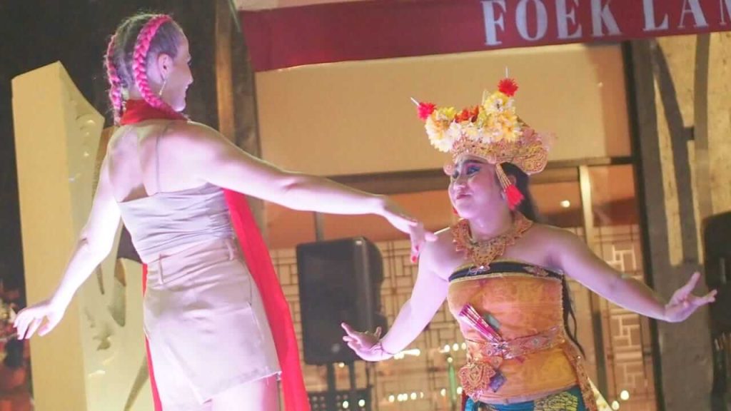 Seorang penari Bali membimbing wisatawan menari di atas panggung Samasta Bali, menciptakan interaksi budaya yang menyenangkan.
