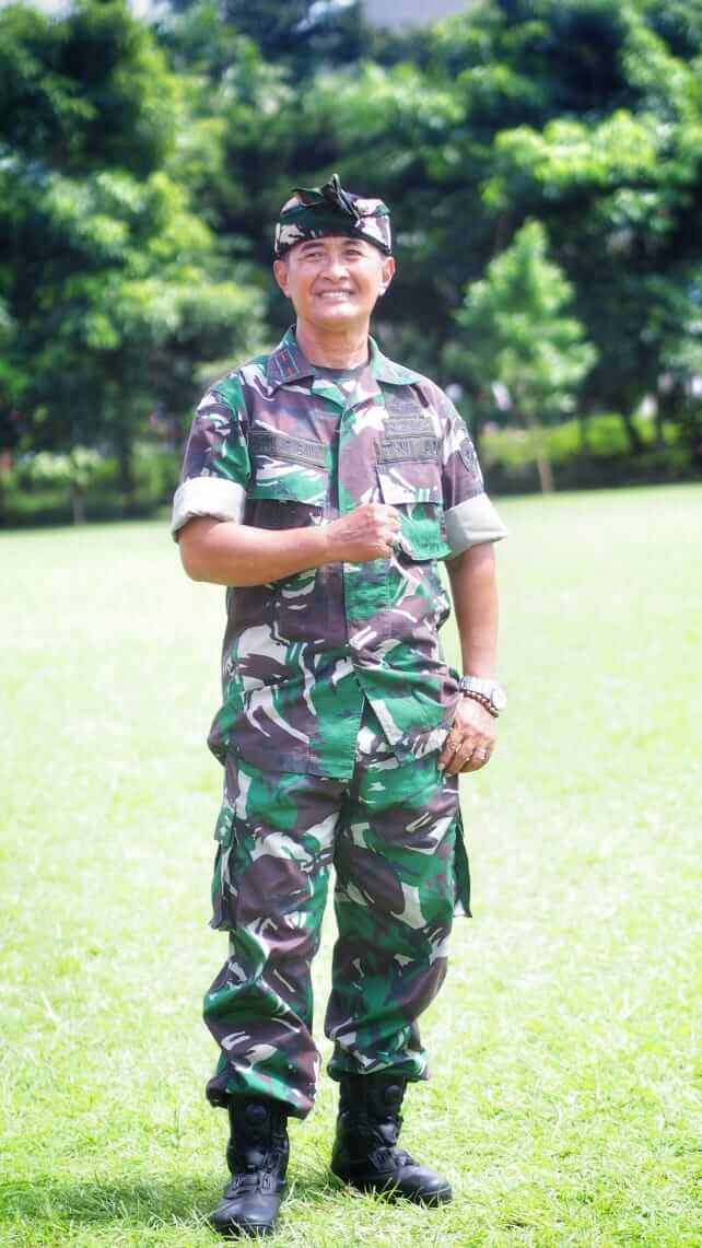 Mayor Arm I Putu Arimbawa, Danramil 1611-03-Kuta, tengah menjalankan tugas dengan wajah serius di tengah kesibukan kerjanya.