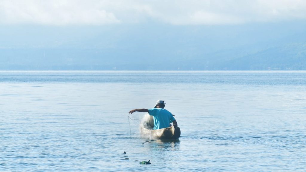 Menebar jaring di danau sebagai simbol usaha dan ketekunan.