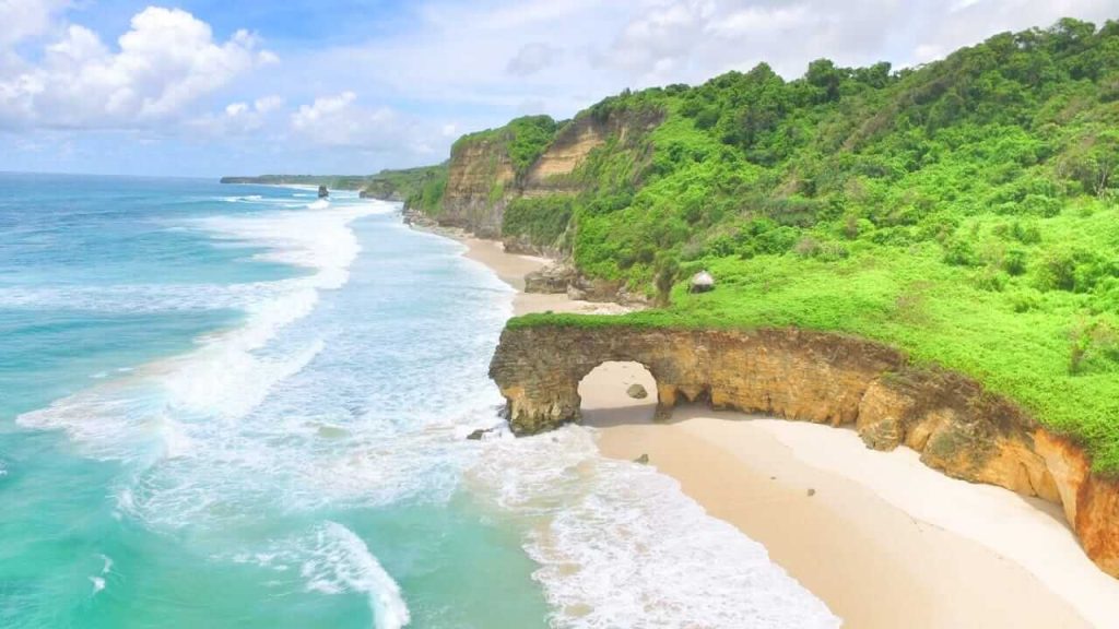 Pantai Bwanna dengan pasir putih luas, tebing megah, dan ombak tenang menciptakan suasana sunyi yang memikat jiwa.