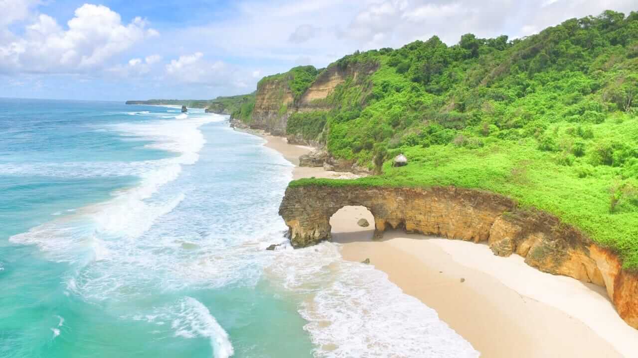 Pantai Bwanna dengan pasir putih luas, tebing megah, dan ombak tenang menciptakan suasana sunyi yang memikat jiwa.