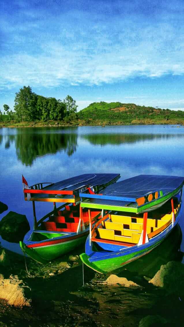 Deretan perahu berlabuh di Danau Ciwidey dengan latar permukaan air yang hening dan pegunungan berkabut.