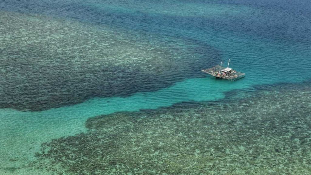 Pemandangan dari puncak Mercusuar Pulau Lengkuas menampilkan laut lepas berwarna biru dan gugusan batu granit yang indah di bawahnya.