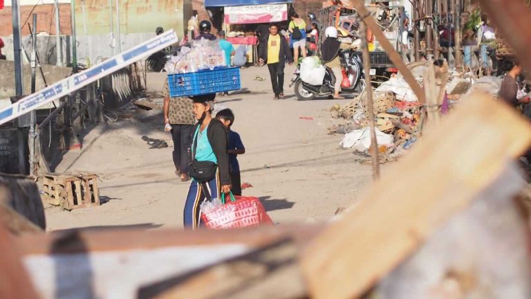 Seorang ibu kembali berjualan meski pasar belum sepenuhnya pulih pascabanjir.