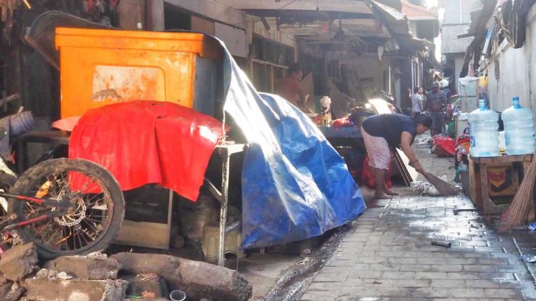 Seorang ibu membersihkan sampah yang menumpuk setelah banjir di Bali.