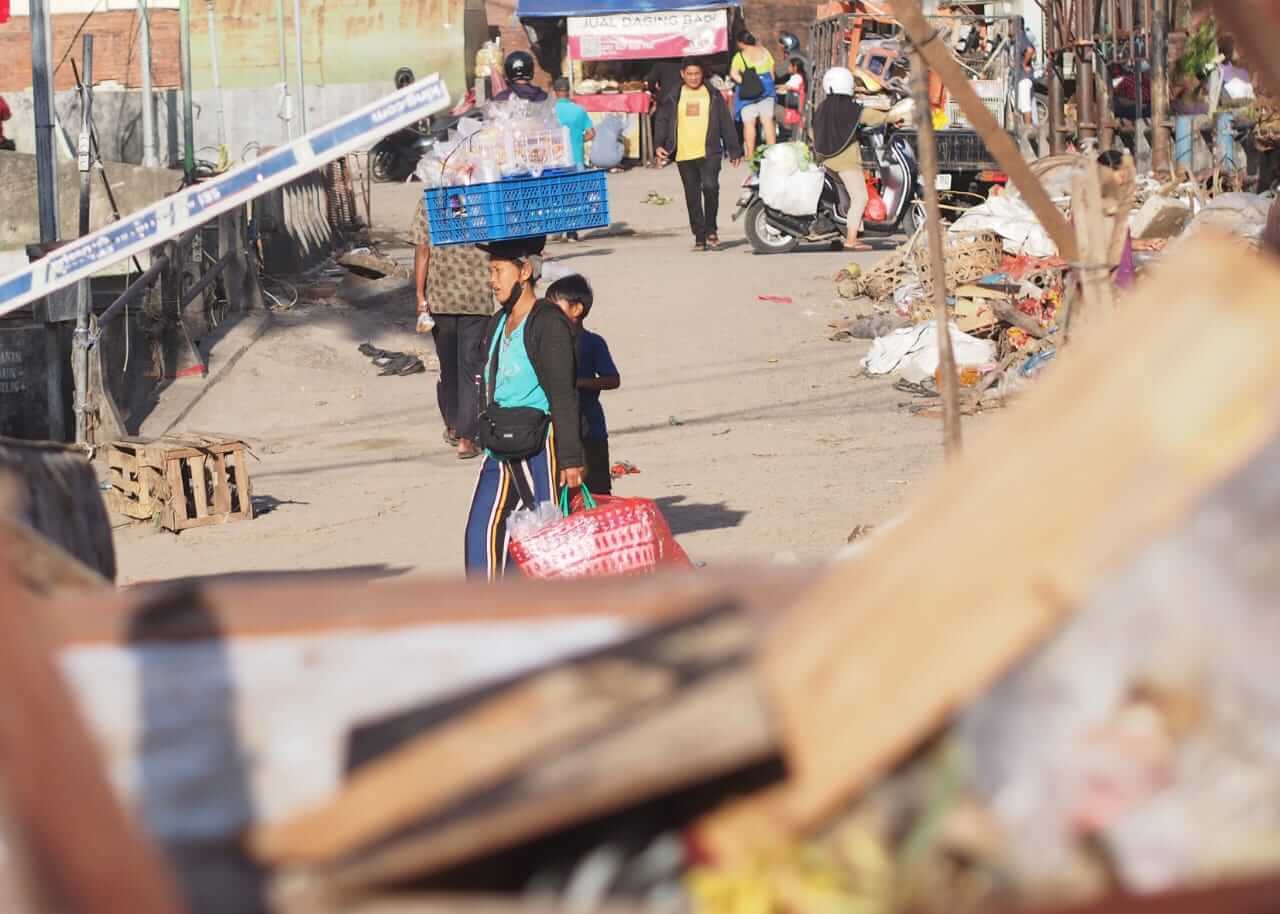 Pedagang melewati lumpur dan barang berserakan di Pasar Kumbasari pascabanjir 10 September 2025.