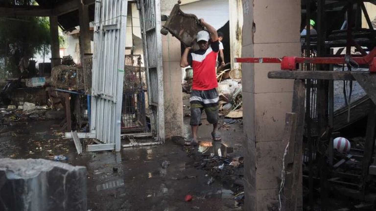 Seorang pria membersihkan perabotan rumah yang terendam banjir di Bali.