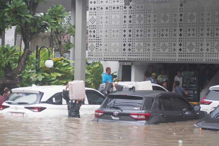 Warga menyaksikan mobil terendam banjir hingga setengah bodi di depan sebuah gedung di Bali.