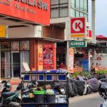 Penjual makanan kaki lima berjualan di tengah keramaian kawasan Seminyak yang dipenuhi kafe dan turis.