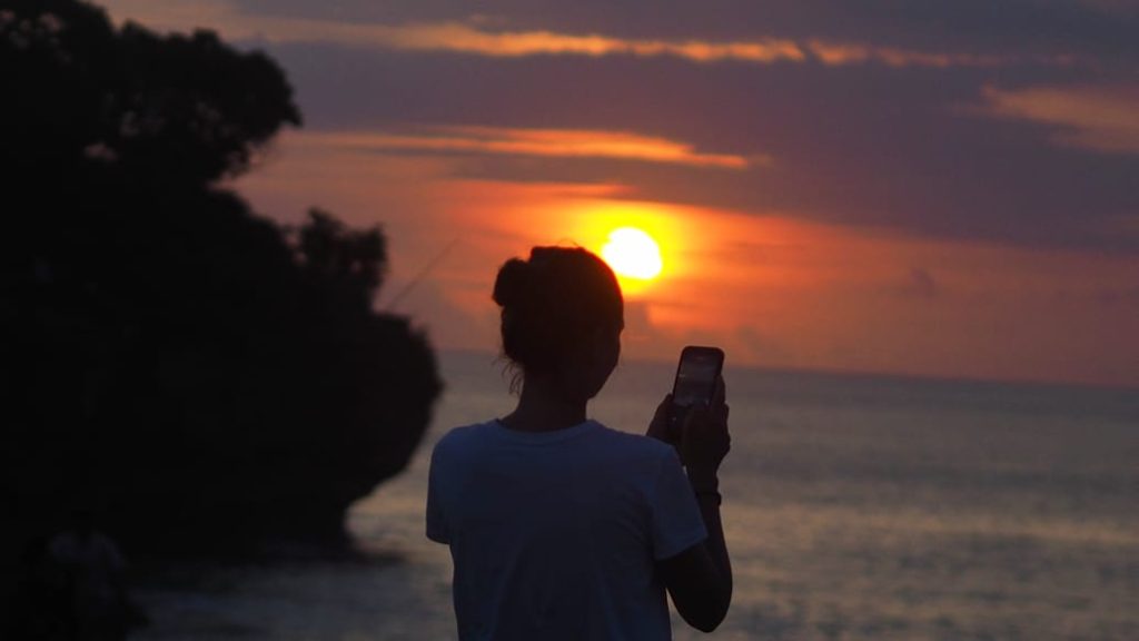 Pemandangan Honeymoon Beach di Jimbaran dengan pasir putih dan tebing karang di sekelilingnya.