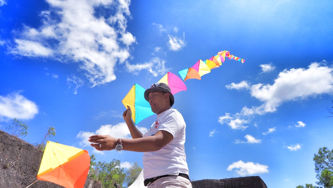 Kadek Armika membantu temannya asal Swedia menerbangkan layangan dalam sebuah acara budaya di Bali.