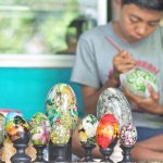 Seorang seniman Bali tengah melukis motif tradisional di atas permukaan telur dengan kuas halus.