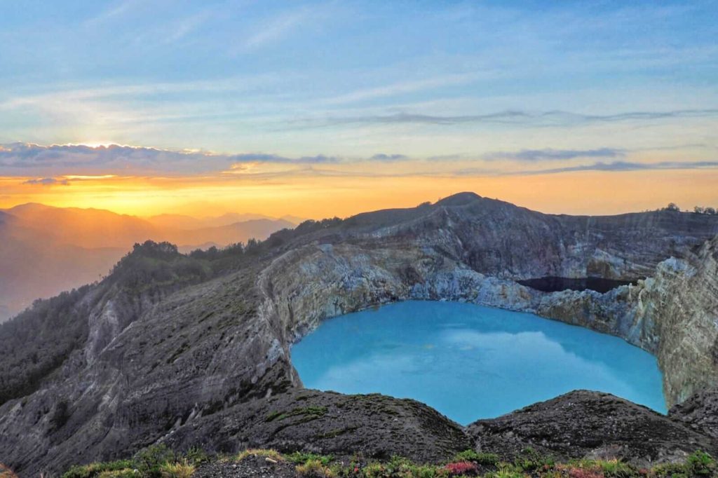 Pemandangan sunrise di Danau Kelimutu dengan cahaya matahari yang menyinari tiga kawah berwarna.