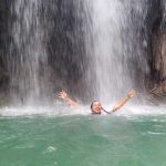 Wisatawan menikmati kesegaran air terjun Mata Jitu di Pulau Moyo, dikelilingi pepohonan hijau yang rimbun.