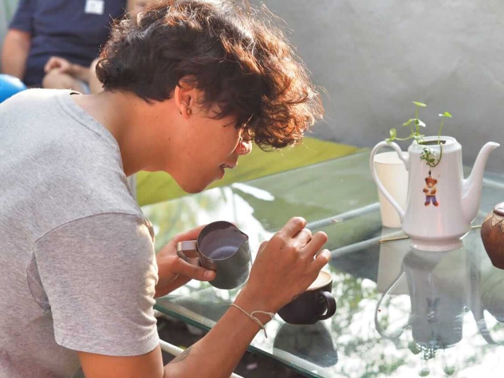 Seorang barista sedang menyeduh kopi dengan penuh ketelitian.