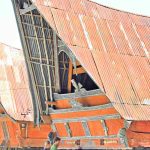 Pemandu lokal menjelaskan makna simbol-simbol pada rumah adat Batak kepada wisatawan.