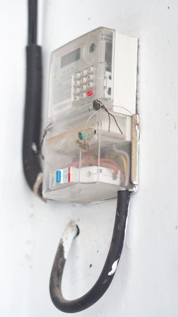 Petugas PLN memeriksa meteran listrik di salah satu rumah warga.