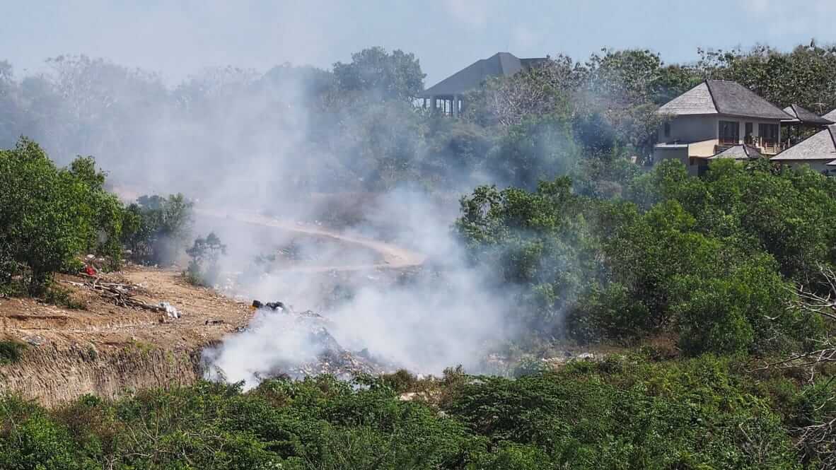 Asap tebal membubung dari tumpukan sampah yang dibakar di Bali, menunjukkan permasalahan pengelolaan limbah yang belum tertangani dengan baik.