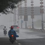 Hujan turun di salah satu ruas jalan di Bali, kendaraan melintas dengan hati-hati di tengah kondisi basah.