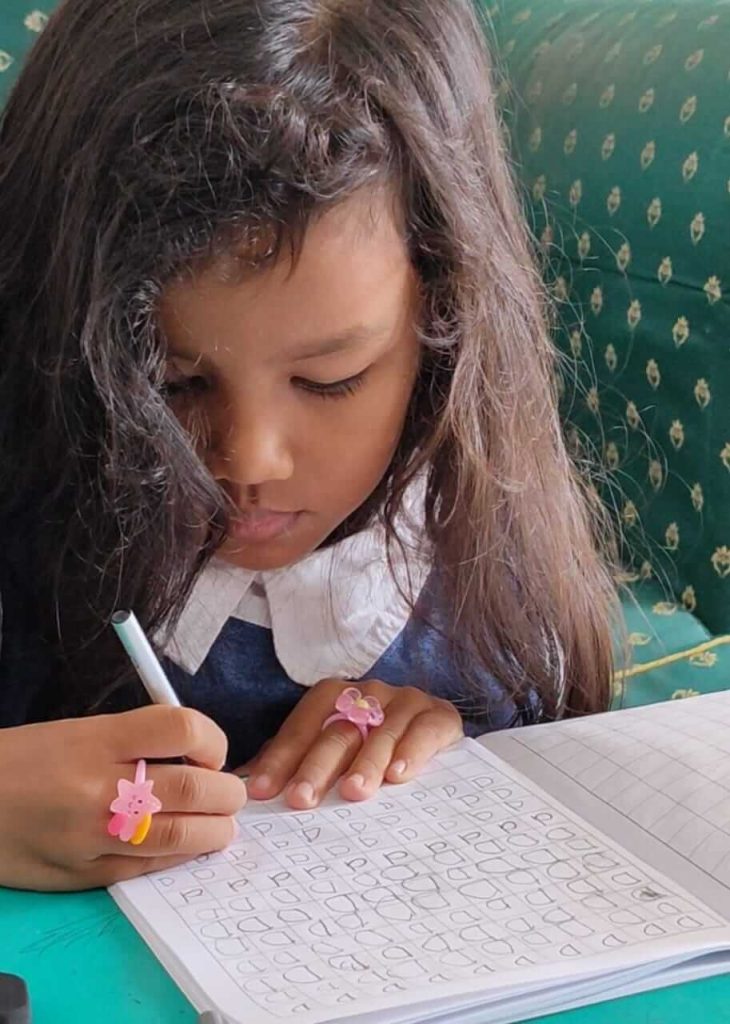 Seorang anak belajar di rumah dengan metode homeschooling, duduk di meja belajar sambil membaca buku.