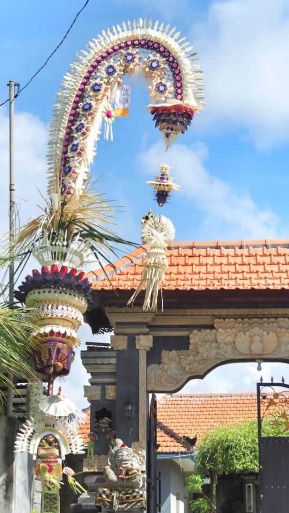 Suasana perayaan Hari Raya Galungan di Bali dengan penjor menghiasi jalanan dan umat yang beribadah di pura.