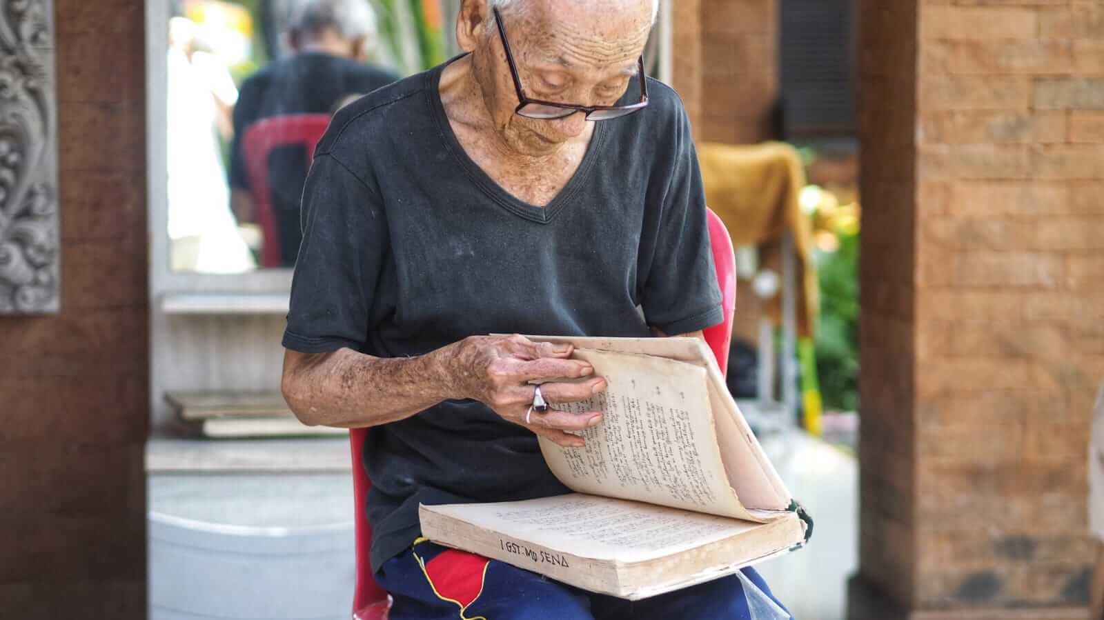 Potret I Gusti Made Sena, pria lansia 97 tahun, duduk tenang dengan ekspresi bijaksana.