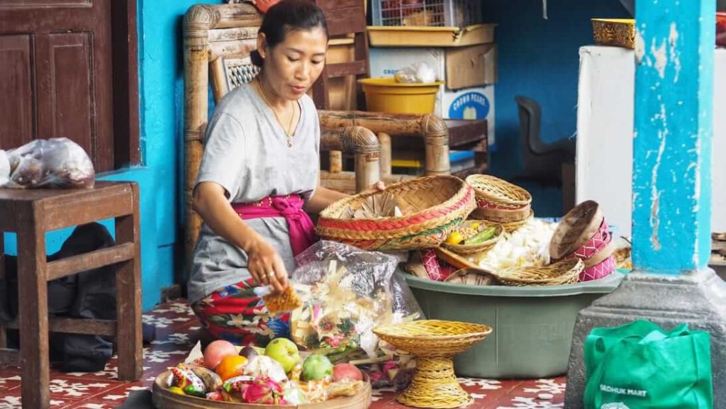 Nyoman Sari memilih buah-buahan segar sambil menyiapkan kue dan jajanan untuk dibagikan kepada keluarga yang datang berkunjung.