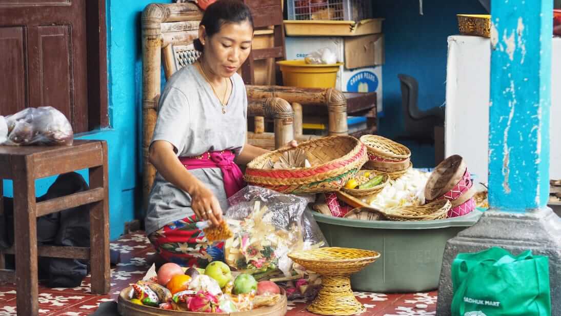Nyoman Sari memilih buah-buahan segar sambil menyiapkan kue dan jajanan untuk dibagikan kepada keluarga yang datang berkunjung.