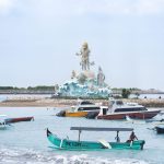 Pemandangan Pantai Jerman dengan garis pantai yang landai dan pesawat yang tampak melintas rendah di kejauhan.