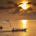 Siluet seseorang berjalan di jalan sepi saat matahari terbenam, menggambarkan perjalanan hidup dan refleksi diri.