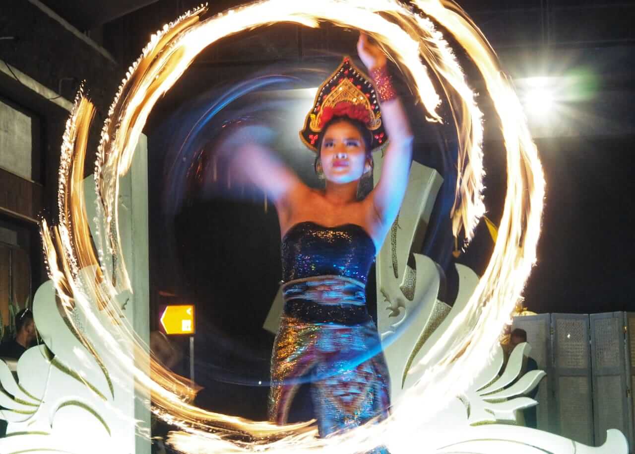 Seorang penari perempuan menampilkan fire dance dengan gerakan anggun dan nyala api yang berputar.