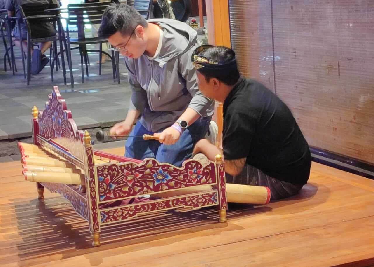 Putu Indra mengajarkan wisatawan cara memainkan rindik dengan suasana hangat dan santai.